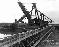 Marine engineers inspecting heavy equipment near a river dredging operation.