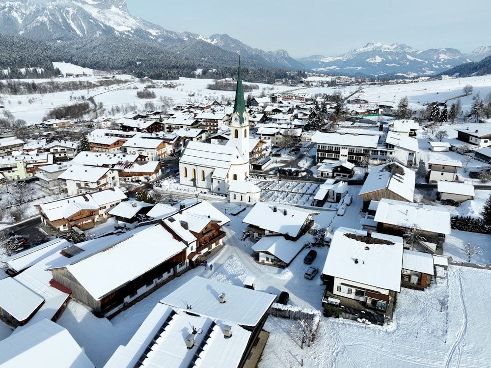 a snowy village with a church and mountains in the background
