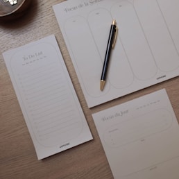 a notepad, pen, and cup on a table