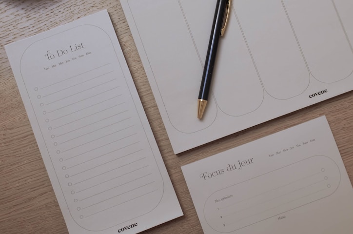 a notepad, pen, and cup on a table