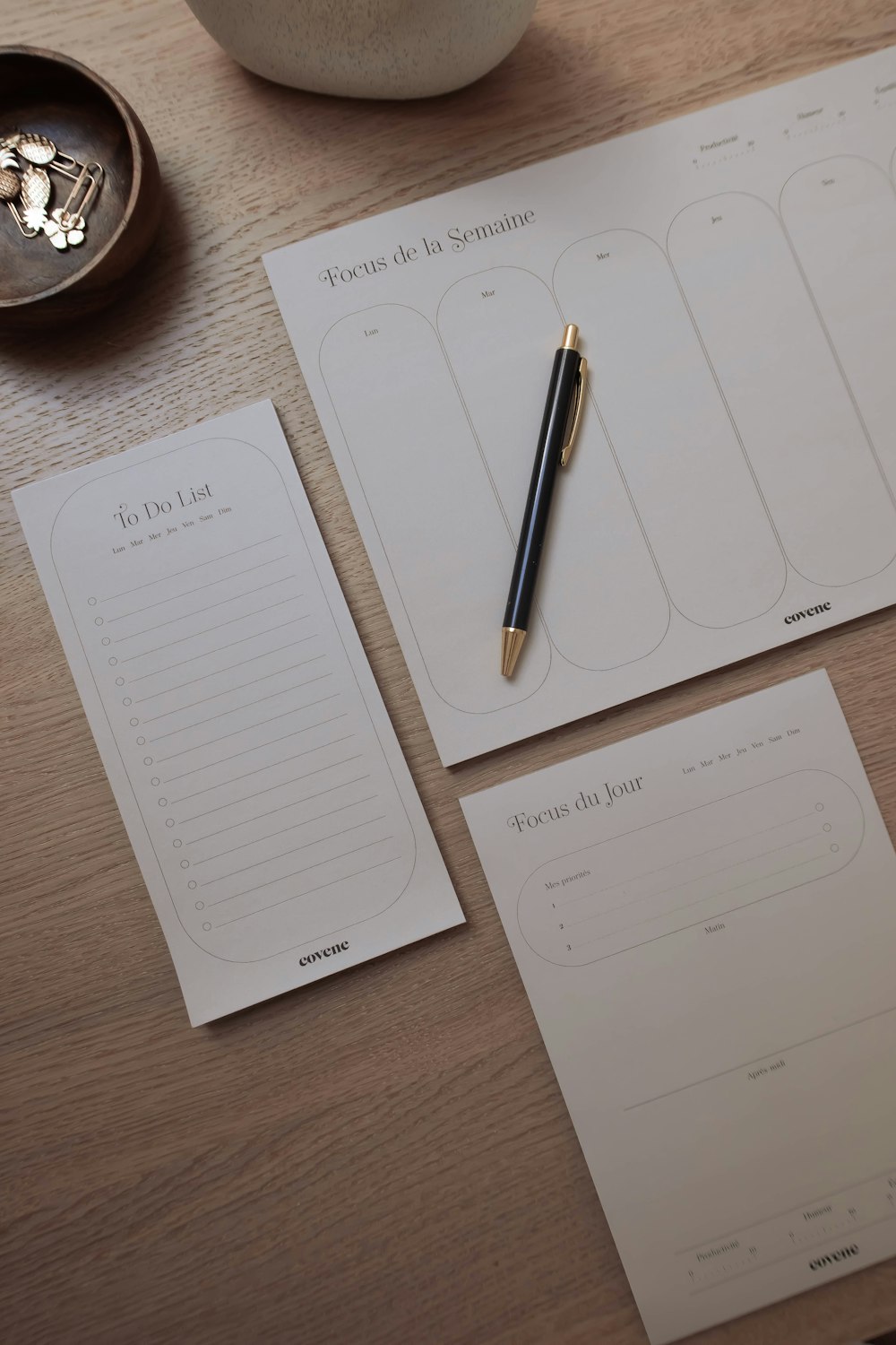 un bloc de notas, un bolígrafo y una taza sobre una mesa