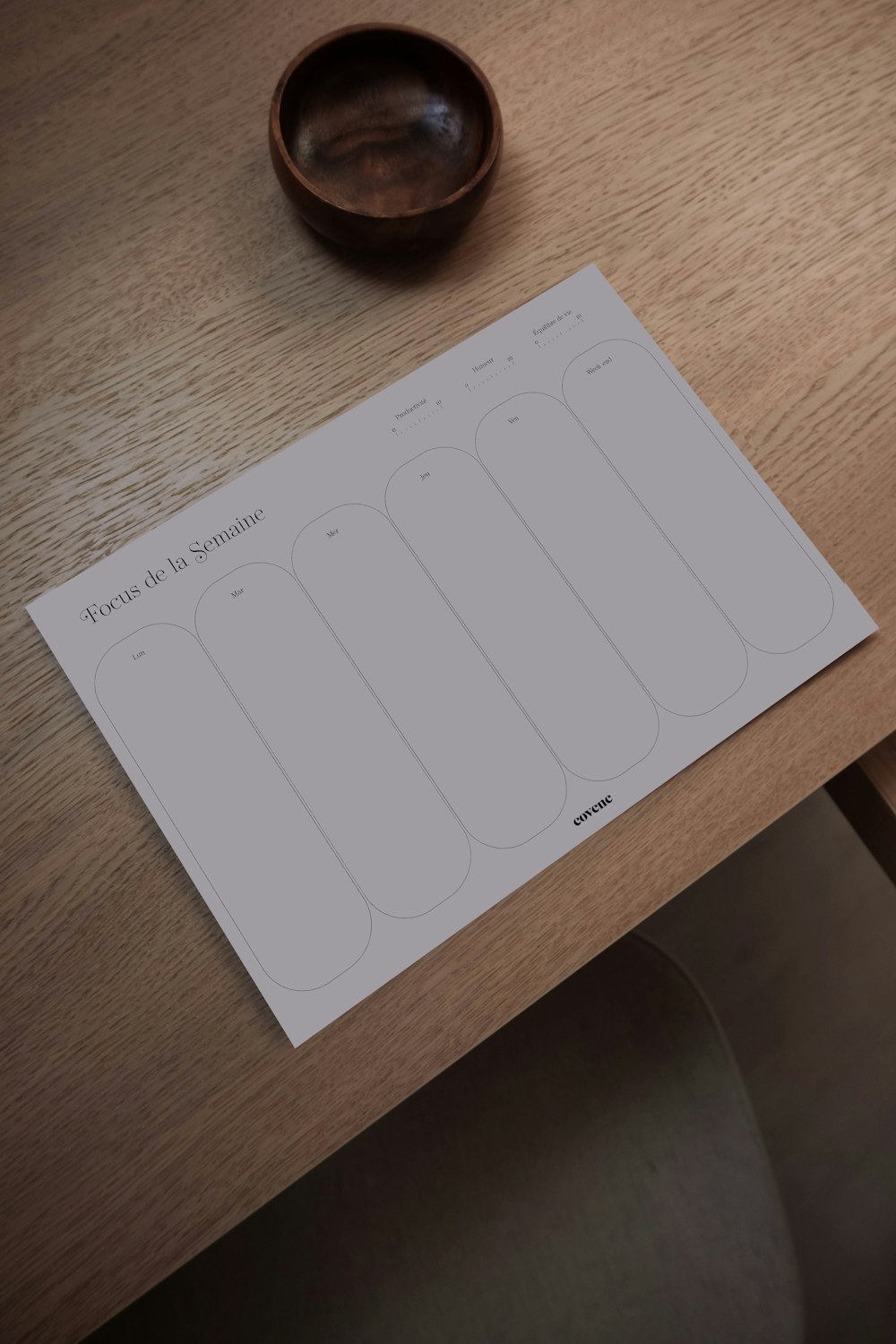 a wooden table with a bowl and paper on it