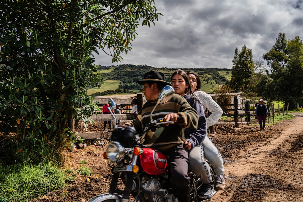 a man and woman riding a motorcycle down a dirt road
