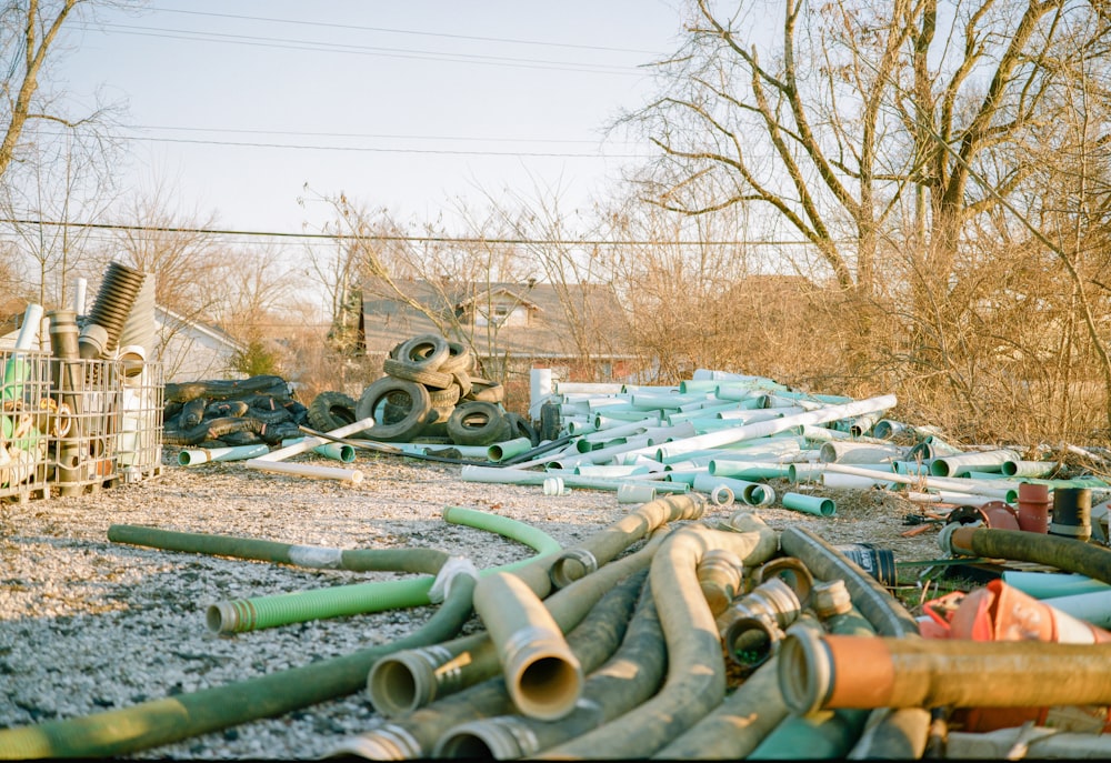 a pile of pipes sitting on top of a dirt field