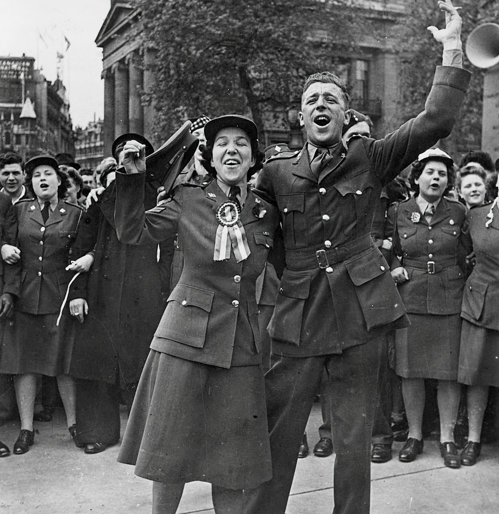 a man and a woman in uniform are standing in front of a group of people