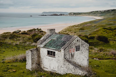 a run down house sitting on top of a lush green hillside Northern Ireland