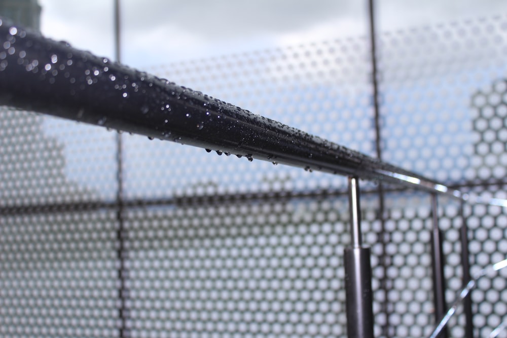 a close up of a metal fence with water droplets on it