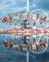 A vibrant amusement park scene with colorful rides spinning under a bright blue sky.