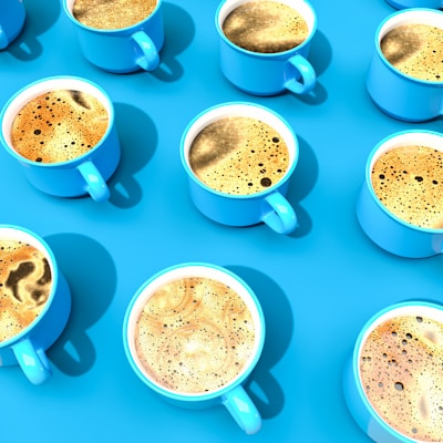 An array of colorful coffee cups showcasing different latte art designs against a bright background.