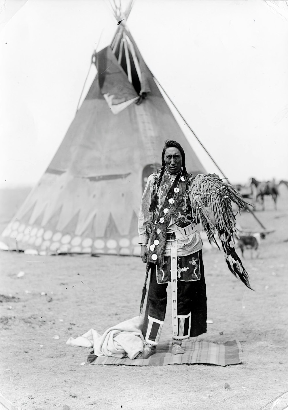 a native american man standing next to a teepee