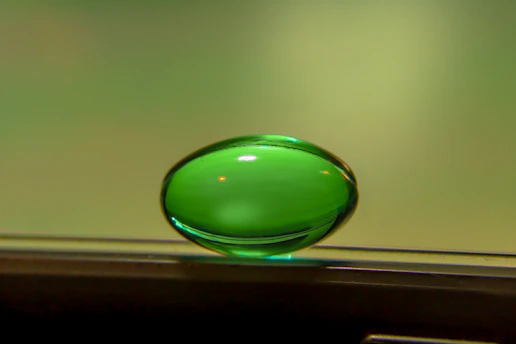 Close-up of a vibrant green emerald button glowing softly against a deep navy blue background, symbolizing health and vitality.