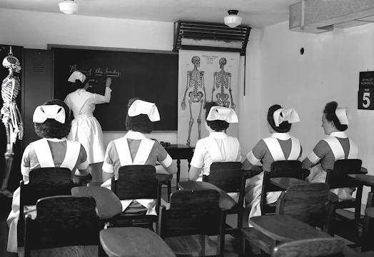 A nurse reviewing a detailed study schedule spread out on a desk.