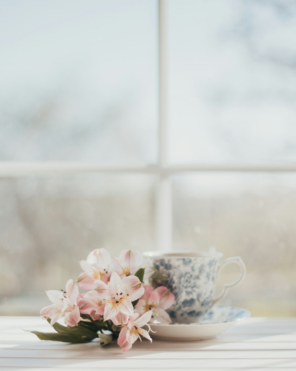 a cup and saucer with flowers on a table