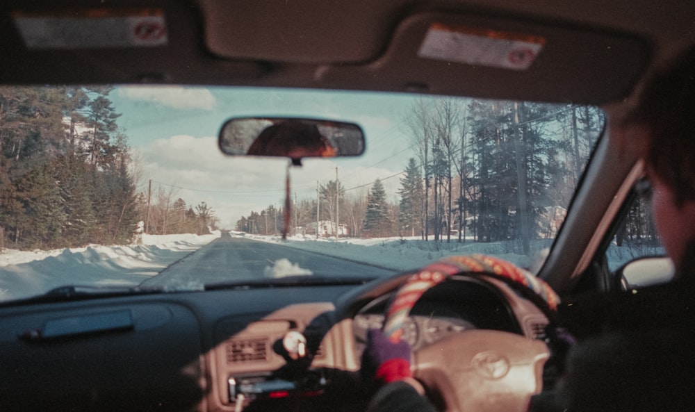 a man driving a car down a snow covered road