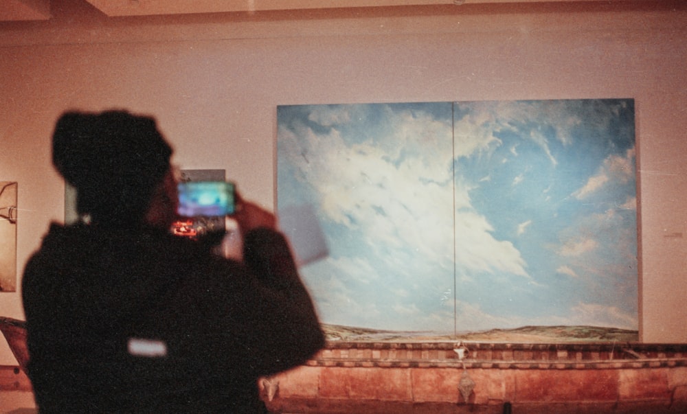 a person taking a picture of a painting on a wall