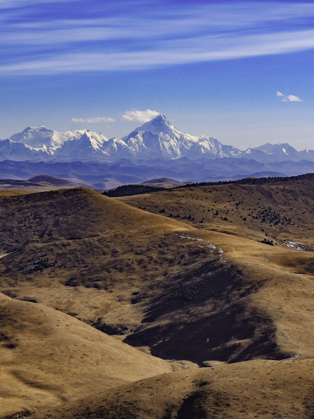 a view of a mountain range with snow capped mountains in the distance