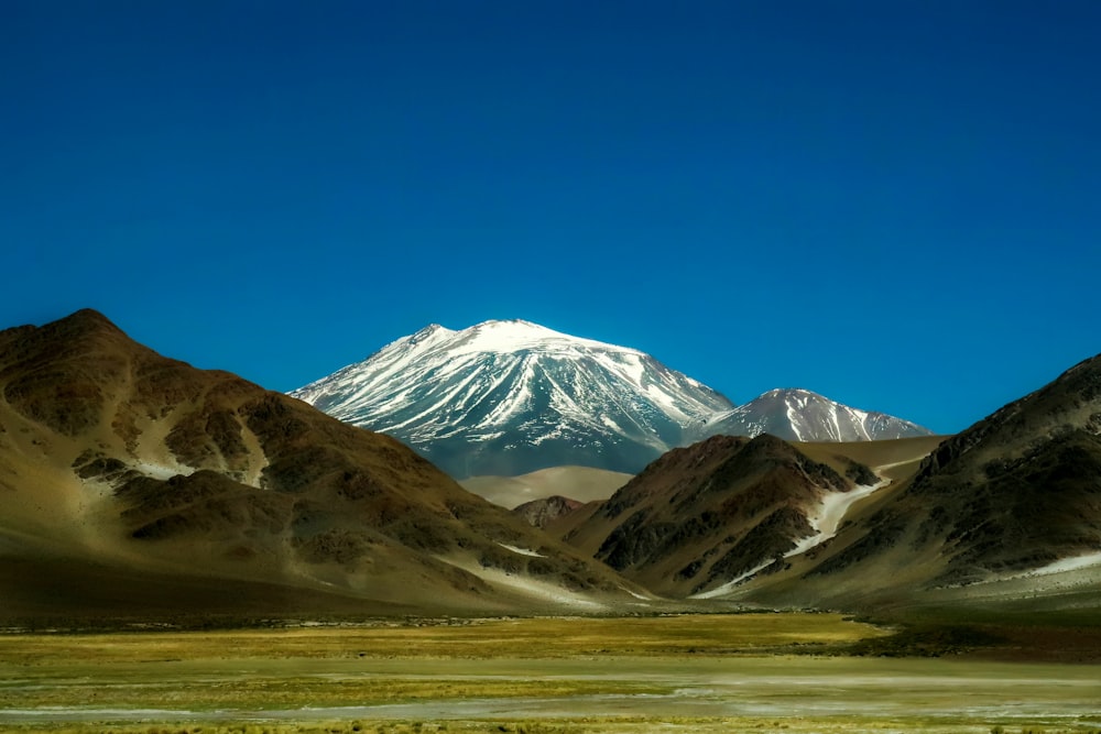 a mountain range with a snow capped peak in the distance