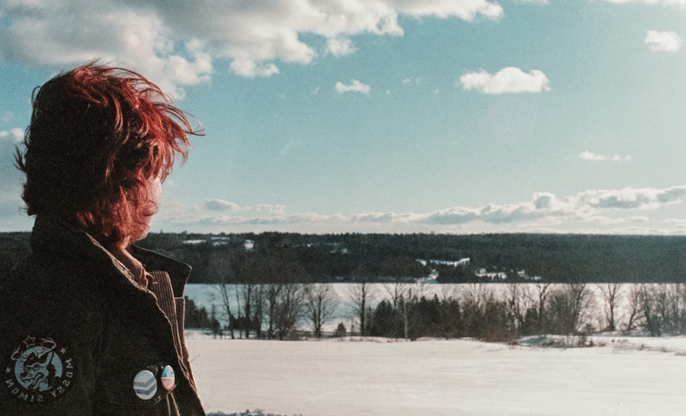 a person with red hair standing in the snow