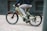 A person is riding a light green electric bicycle with the brand name 'Levit' visible on the frame. The cyclist is dressed casually in a dark top and light gray pants, moving swiftly on a paved surface. The background is slightly blurred, suggesting motion.