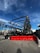 Several large construction lifts are parked in an outdoor lot, each with long extendable arms. Bright red barricades are placed in front of the machinery. The sky above is a clear, vivid blue with some wispy clouds.