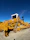 A heavy-duty bulldozer in action with a clear blue sky background at a quarry site.