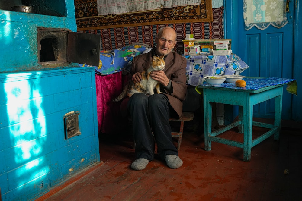 a man sitting on a chair holding a cat
