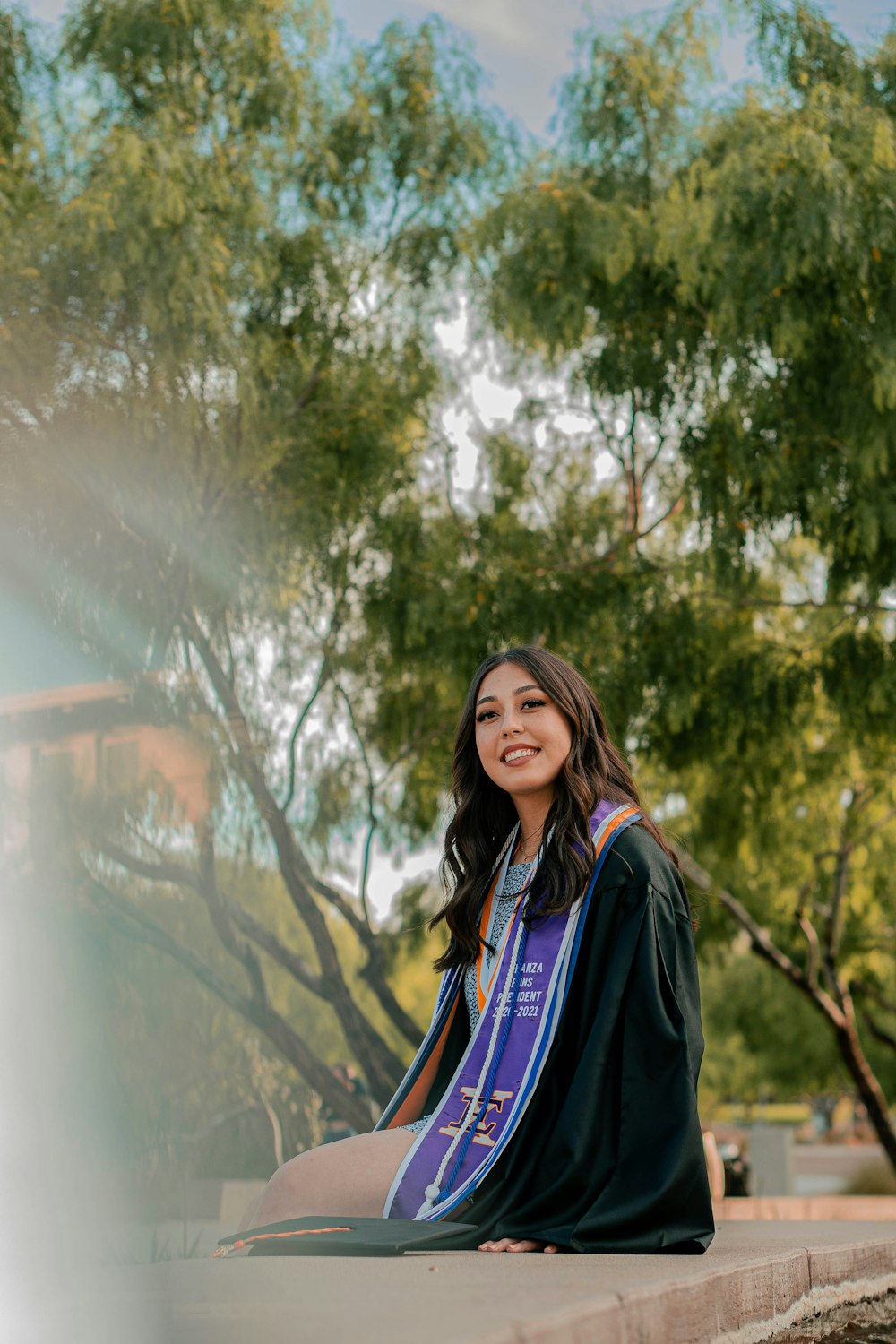 a woman in a graduation gown sitting on a ledge