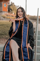 a woman in a graduation gown sitting on steps