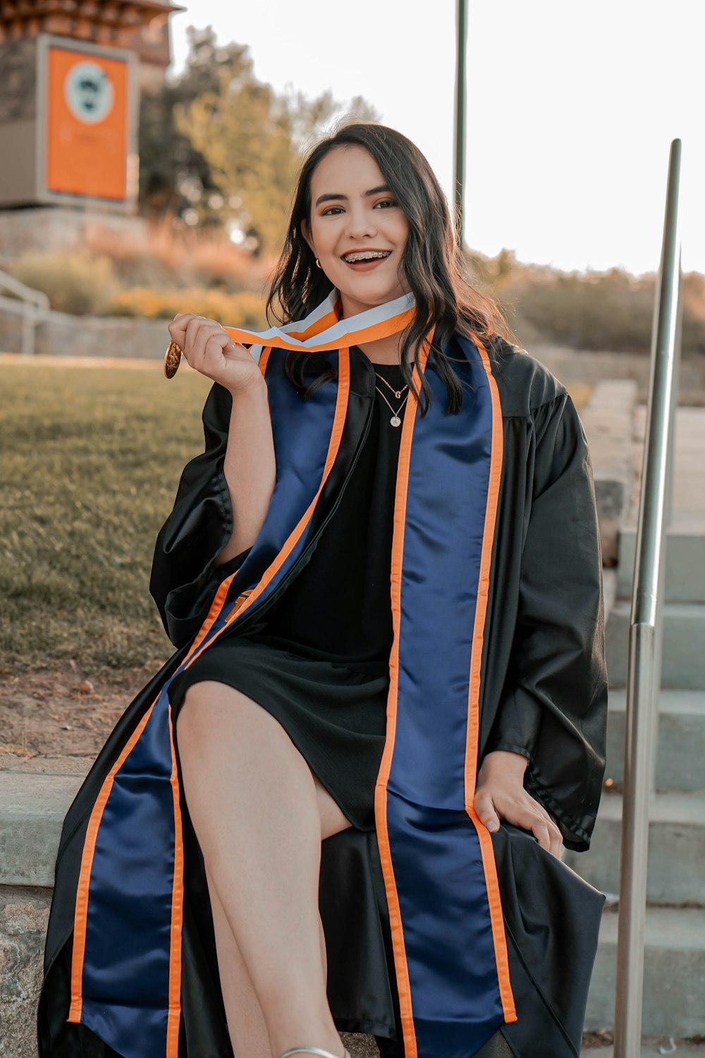 a woman in a graduation gown sitting on steps