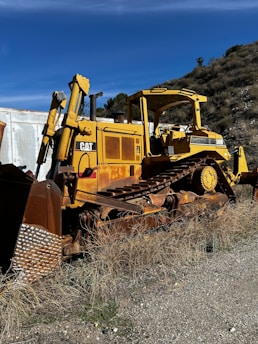 A rugged bulldozer clearing dense brush on a sunny Texas property.