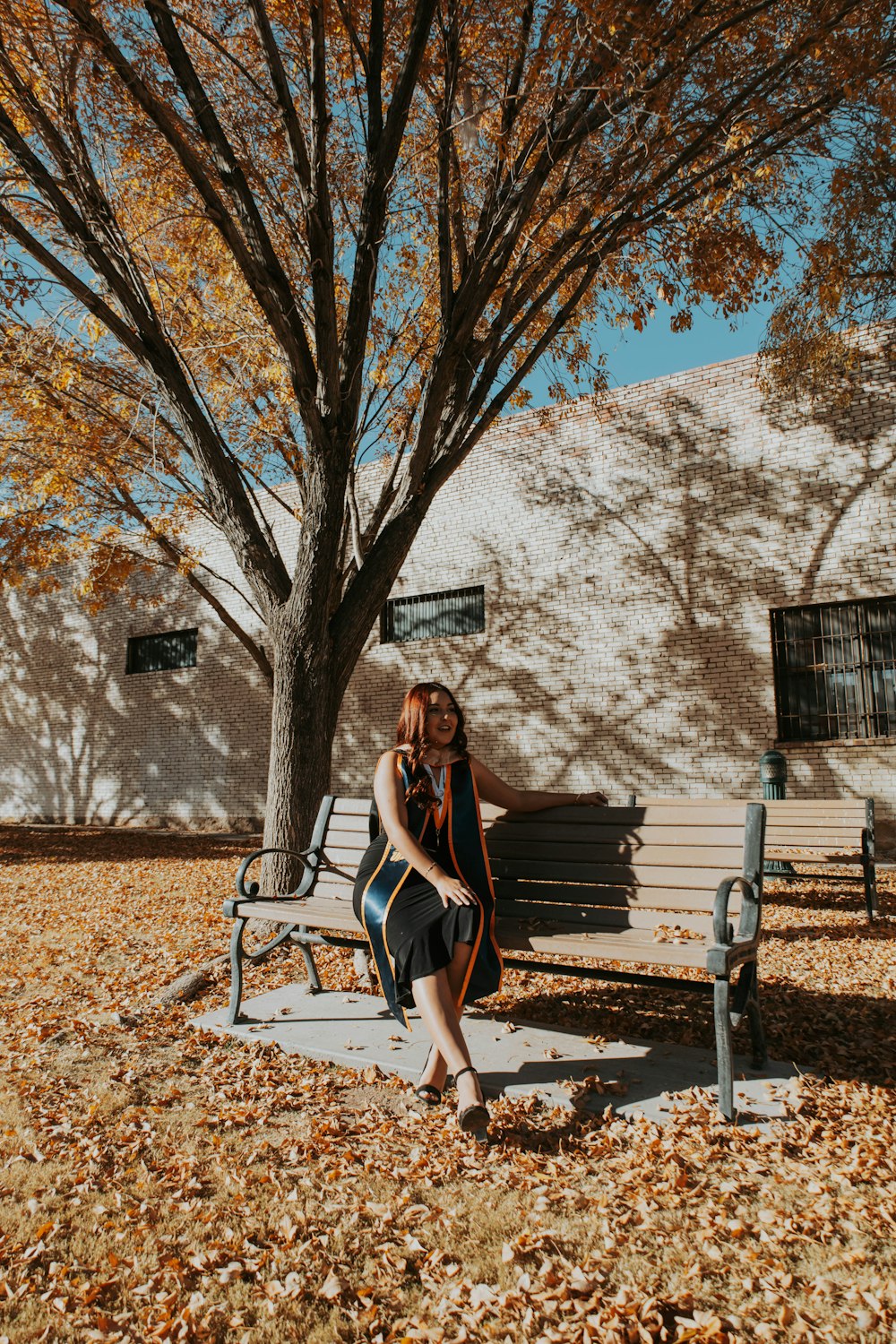 a woman sitting on a bench in front of a tree