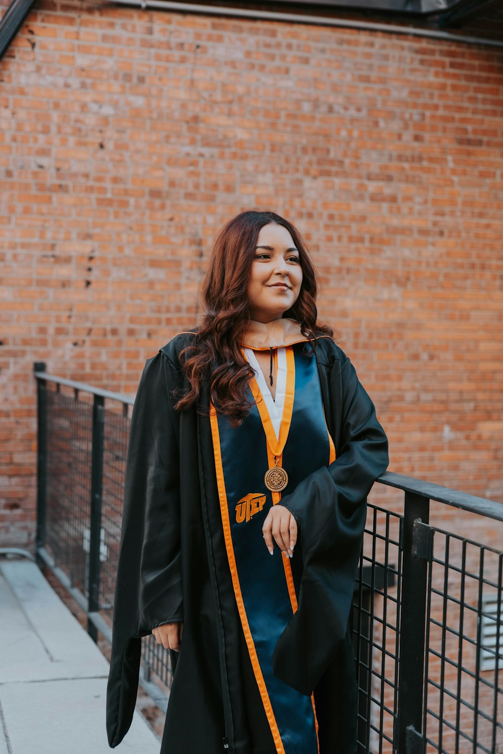 a woman in a graduation gown standing on a sidewalk