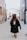 A person wearing a graduation cap and gown walks down an empty, narrow urban alleyway lined with brick buildings. The scene evokes a sense of solitude and contemplation as they move forward.