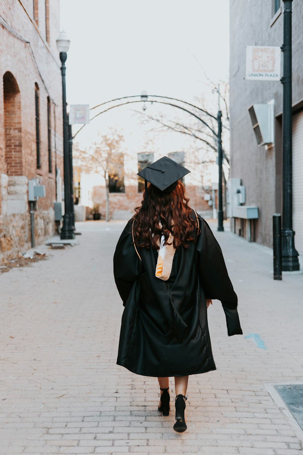 a woman in a graduation gown walks down the street
