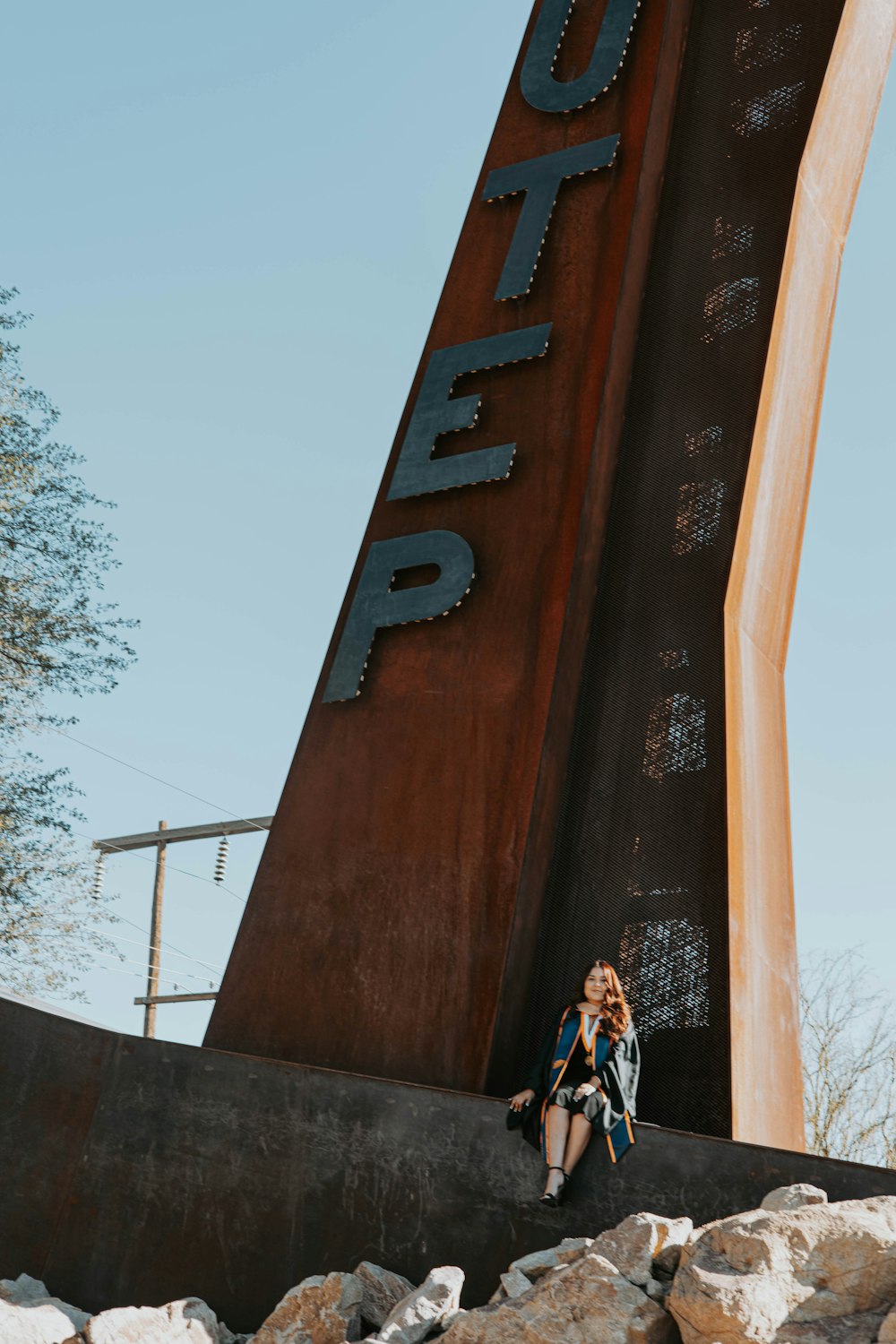 a woman sitting on a rock next to a large sign