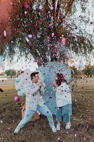 a man and a woman sitting on a bench under a tree surrounded by confe