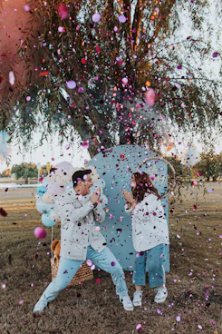 a man and a woman sitting on a bench under a tree surrounded by confe