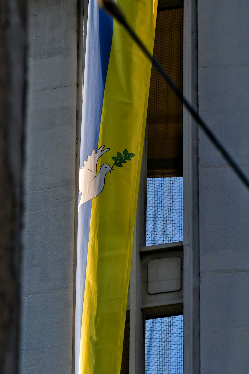 a yellow and blue flag hanging from the side of a building