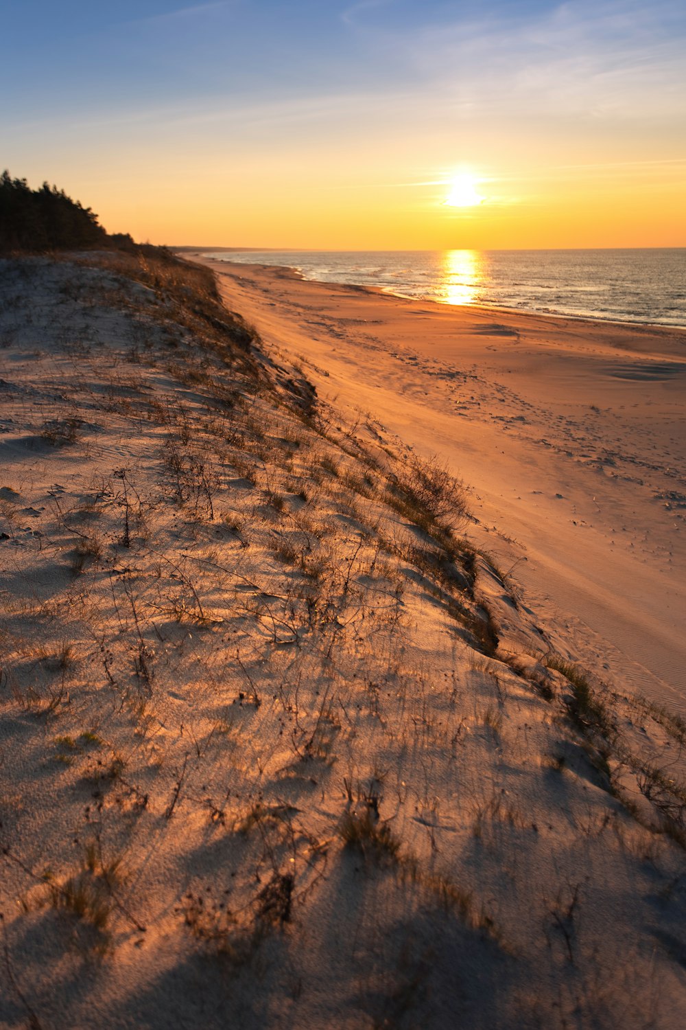 the sun is setting over the beach and sand