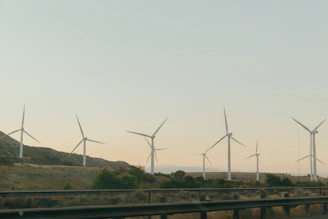 Wind turbines turning gently against a clear blue sky in a rural landscape.