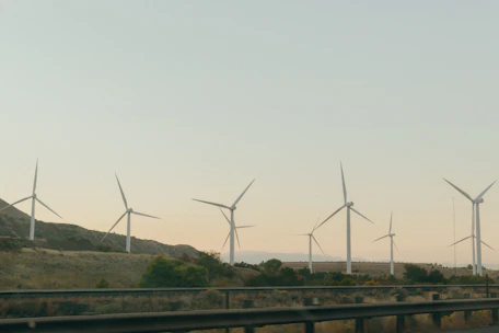 Wind turbines turning gently against a clear blue sky in a rural landscape.