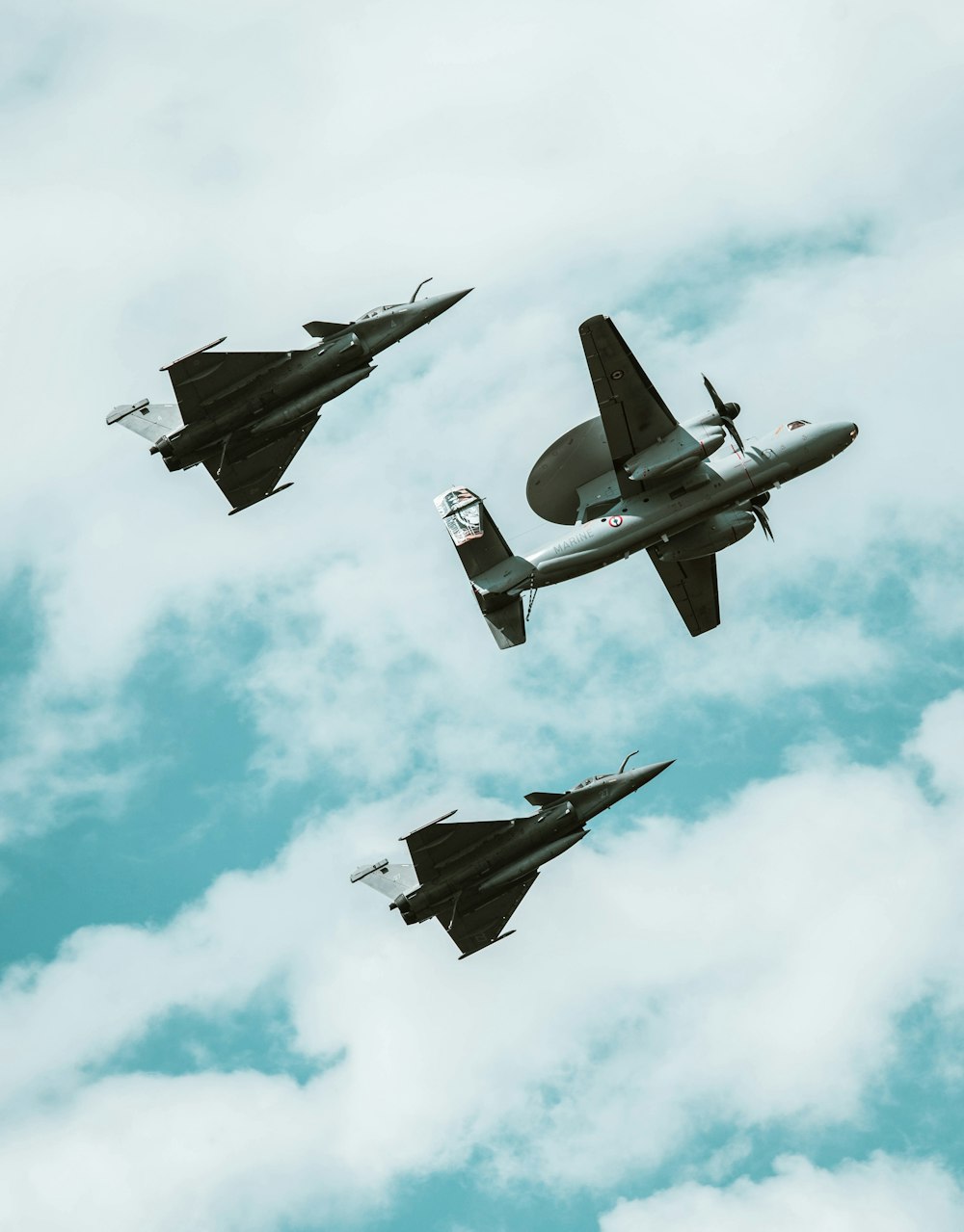 a group of fighter jets flying through a cloudy sky