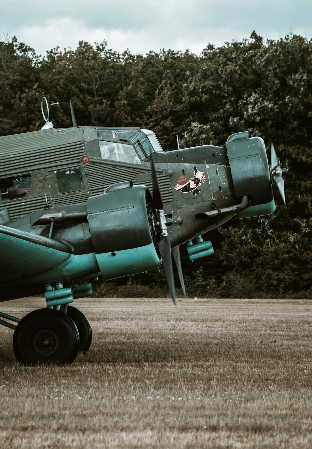 a green airplane sitting on top of a grass covered field