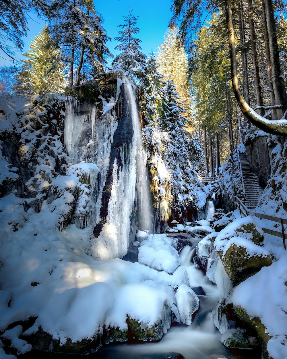 a waterfall in the middle of a snowy forest