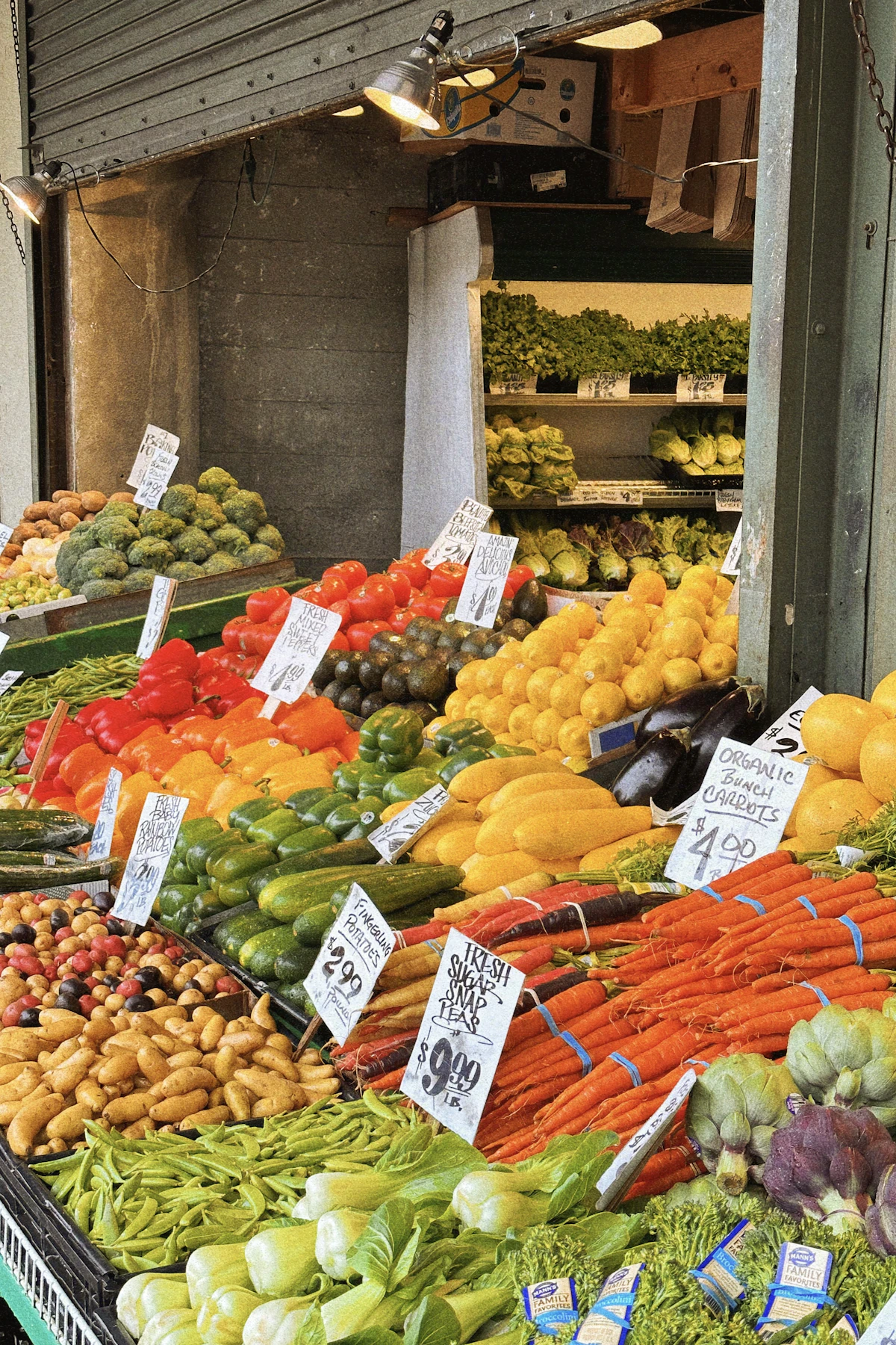Rows of fresh produce with hand-written price cards at an open-air market stall, the kind of cash-based small business the CDB programme is built to reach