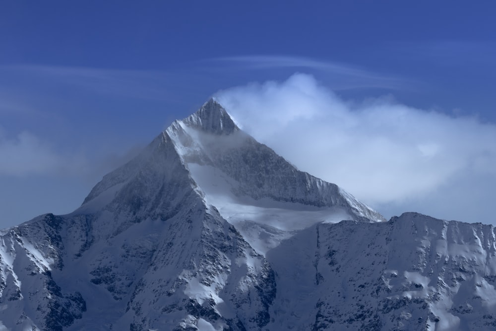 a snow covered mountain with a cloud in the sky