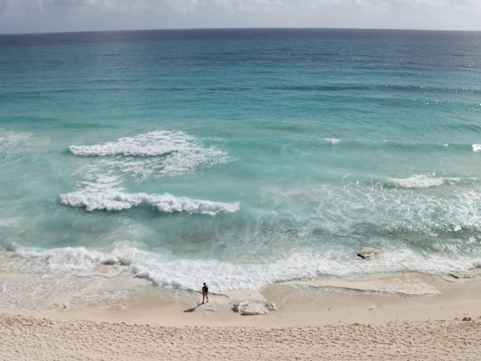 A person standing on a beach next to the ocean — Cancun, Mexico