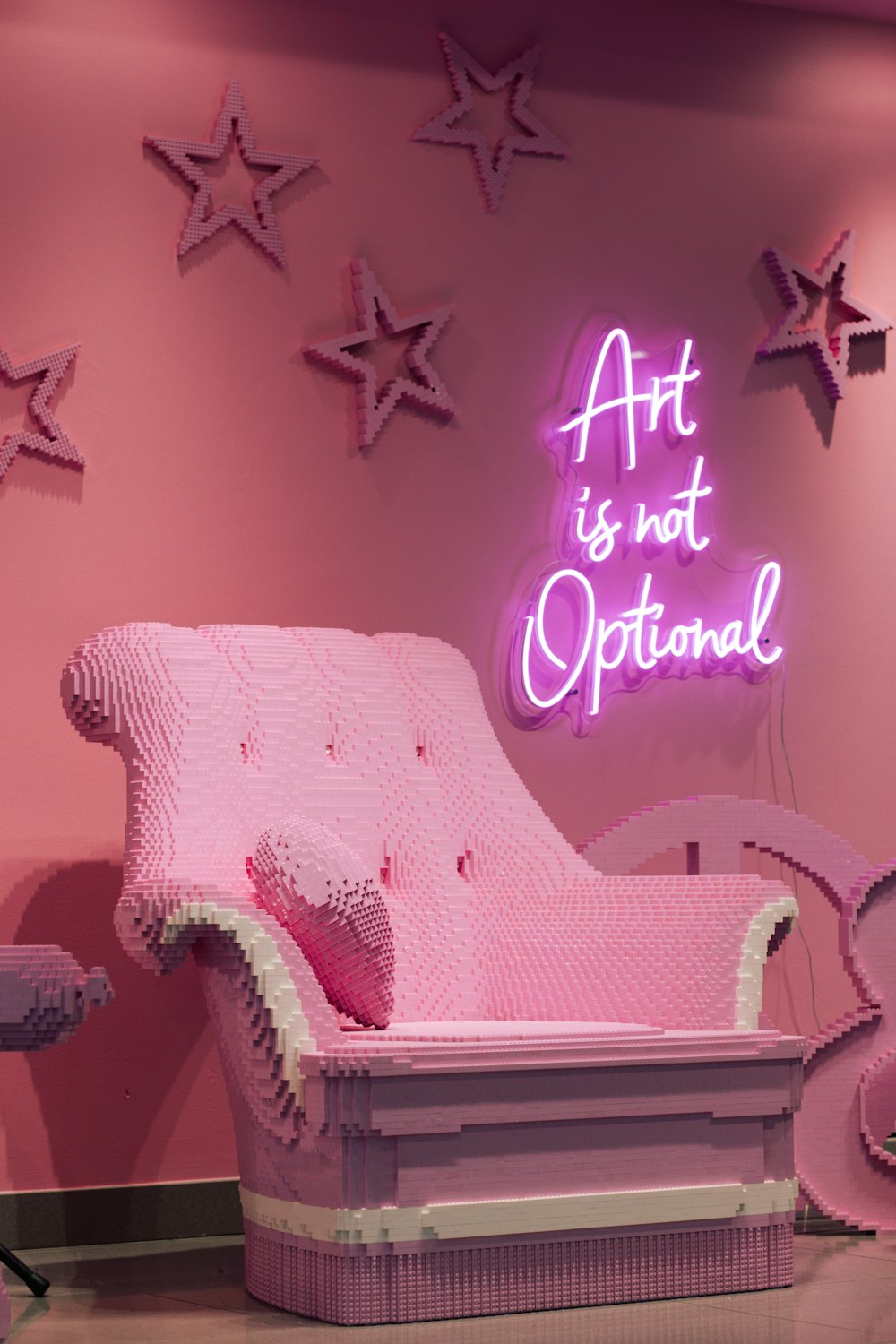 a pink chair sitting in front of a neon sign