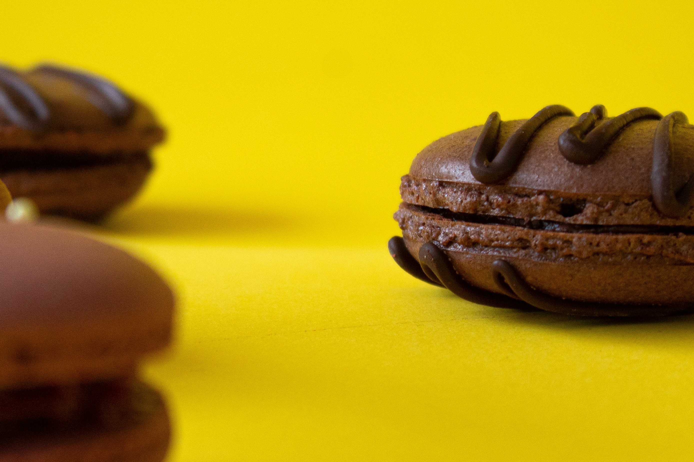 a chocolate doughnut with chocolate frosting on a yellow background