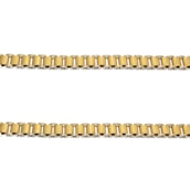Two parallel gold chains are positioned horizontally against a plain white background. The links of the chains are cylindrical and interconnected evenly.